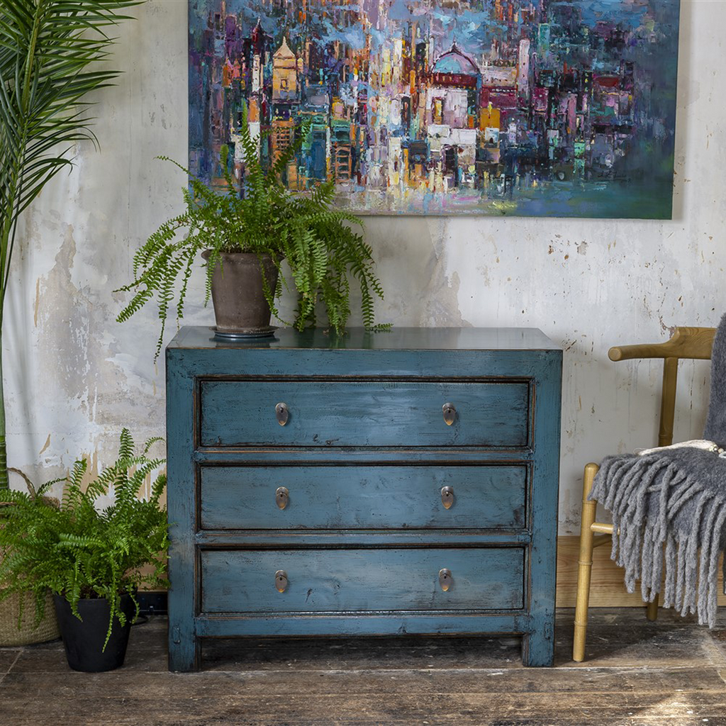 hampton blue chest of drawers in a lovely distressed setting. styled with abstract oil painting and fern plants