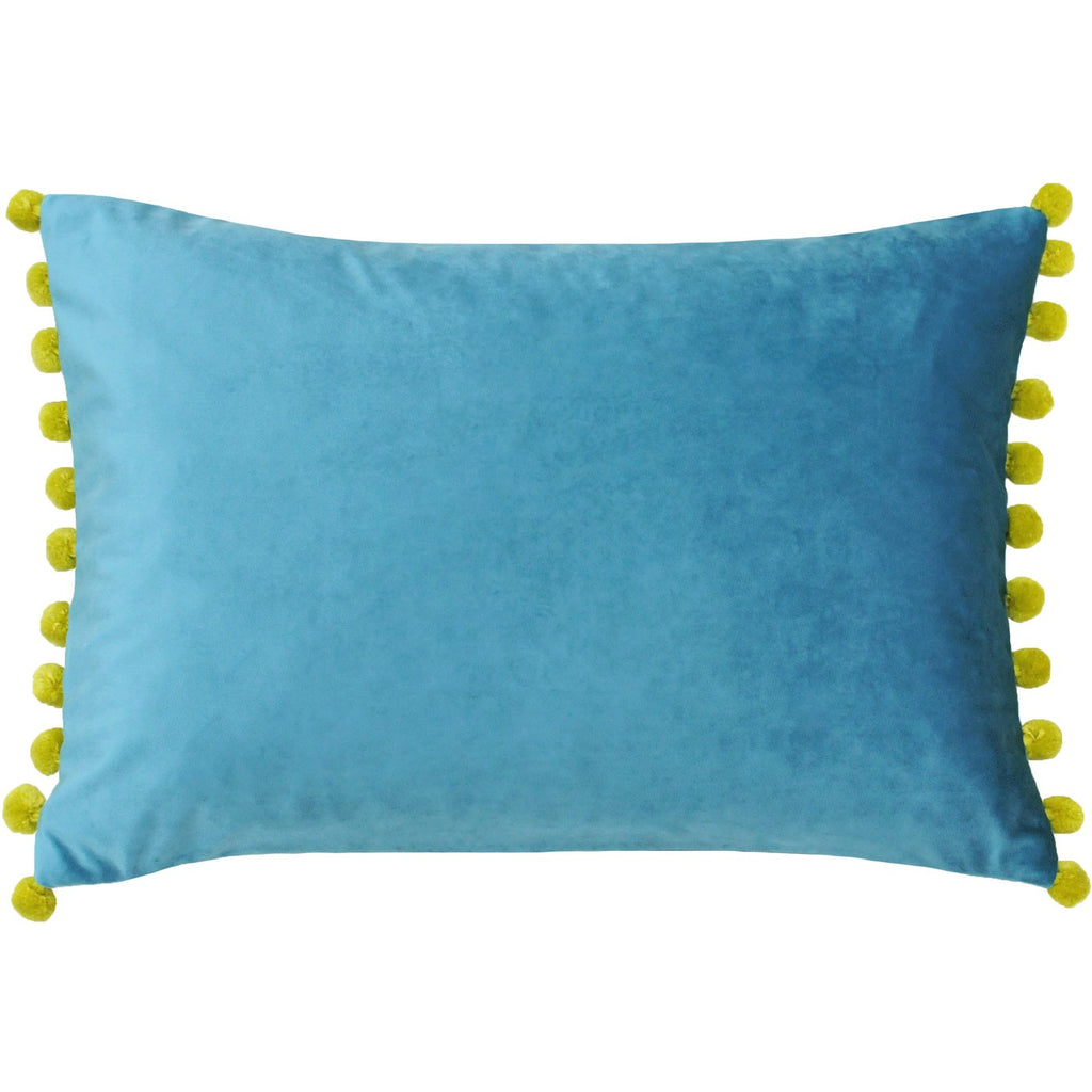 A rectangular cushion with a velvet turquoise cover edged on two sides with yellow pompoms. 