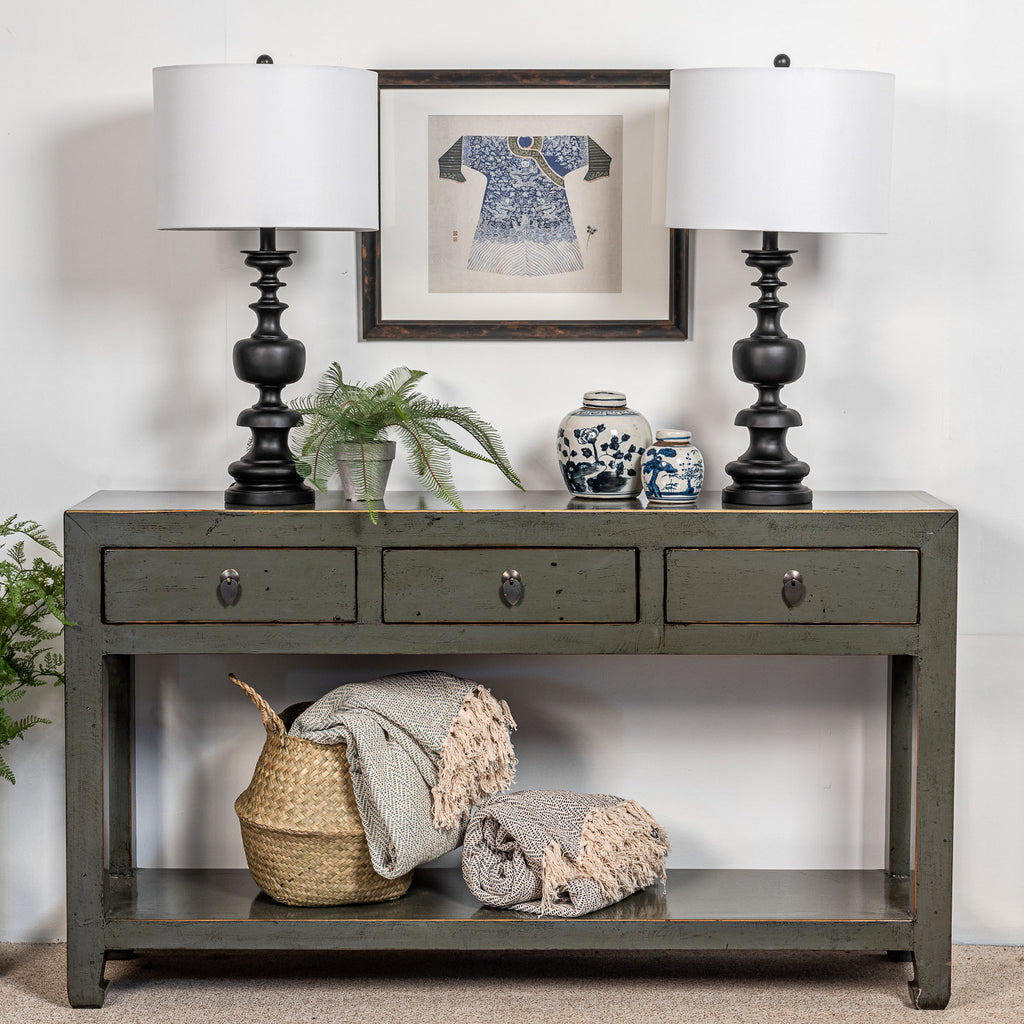 A compact three drawer console table with a shelf and finished in a grey lacquer. 
