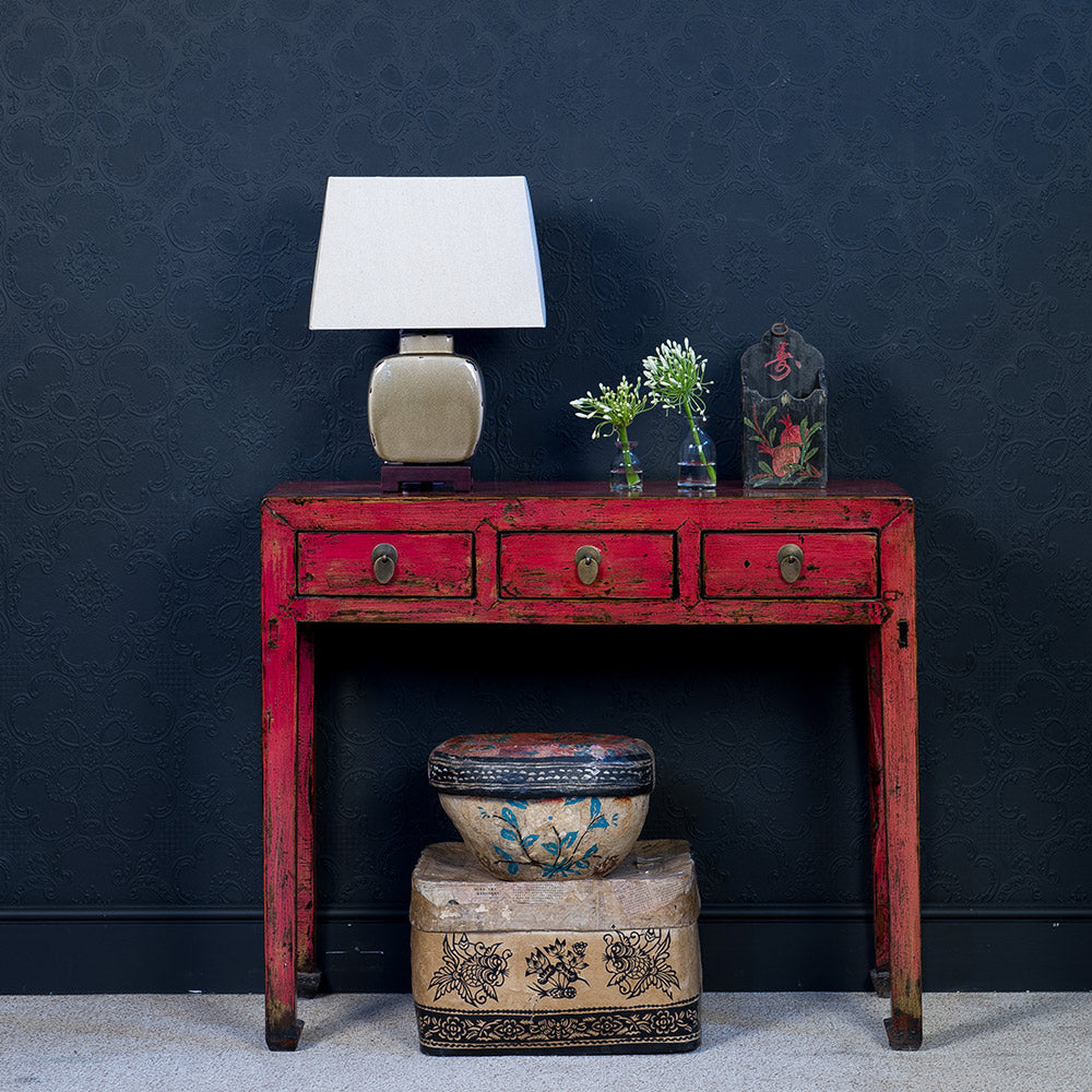 Chinese red antique console table finished with distressed lacquer. styled with gold ceramic lamp and decorated paper mache boxes