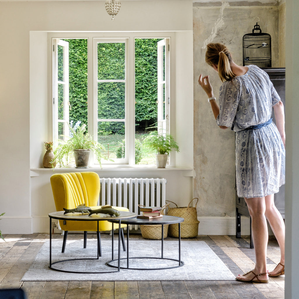 mimmi brink overseeing interior styling photoshoot. image depicts metal coffee tables, yellow velvet arm chair in the middle of the room