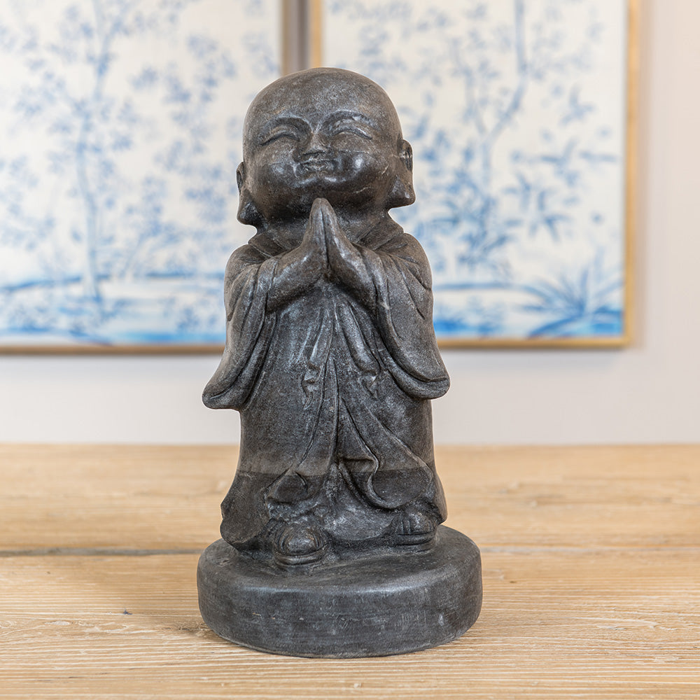 A handmade granite statue of a Chinese Monk, praying with eyes closed and hands together. 