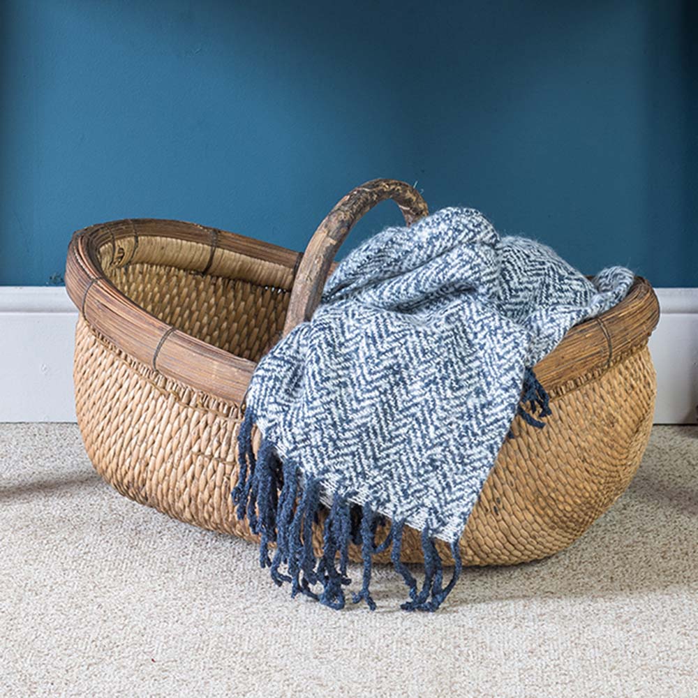 An antique, natural-coloured wicker basket with bamboo upright handle. 
