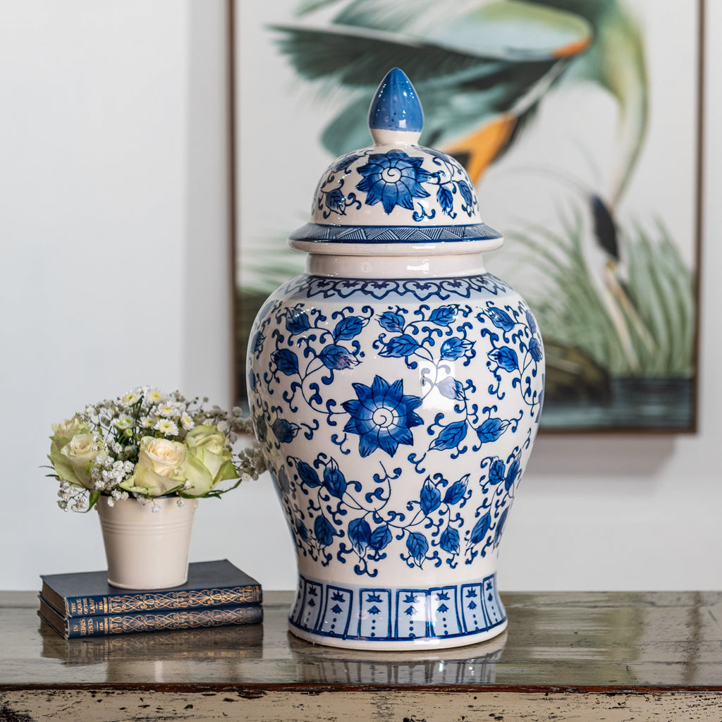 A tall ceramic temple jar, hand-painted with a blue and white floral design. 