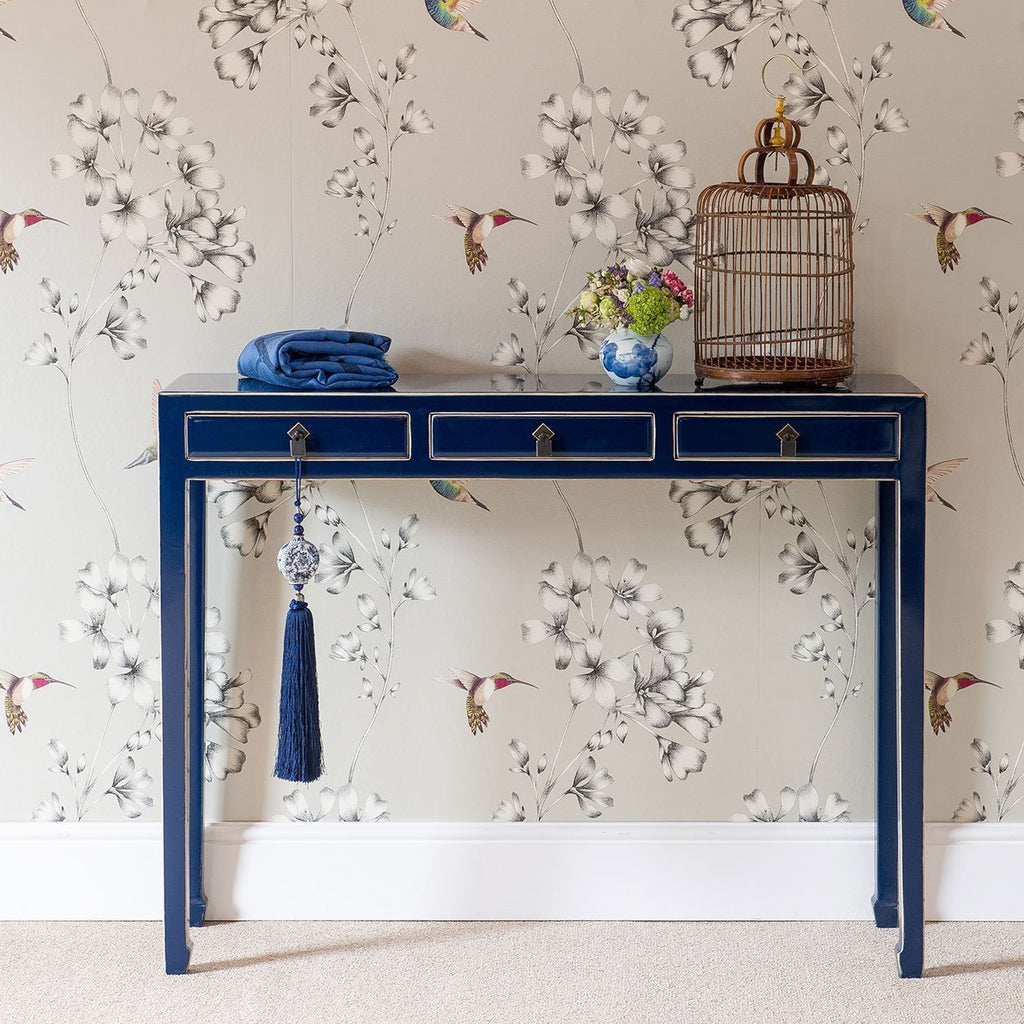 An indigo lacquered console table with three drawers and brass hardware. 