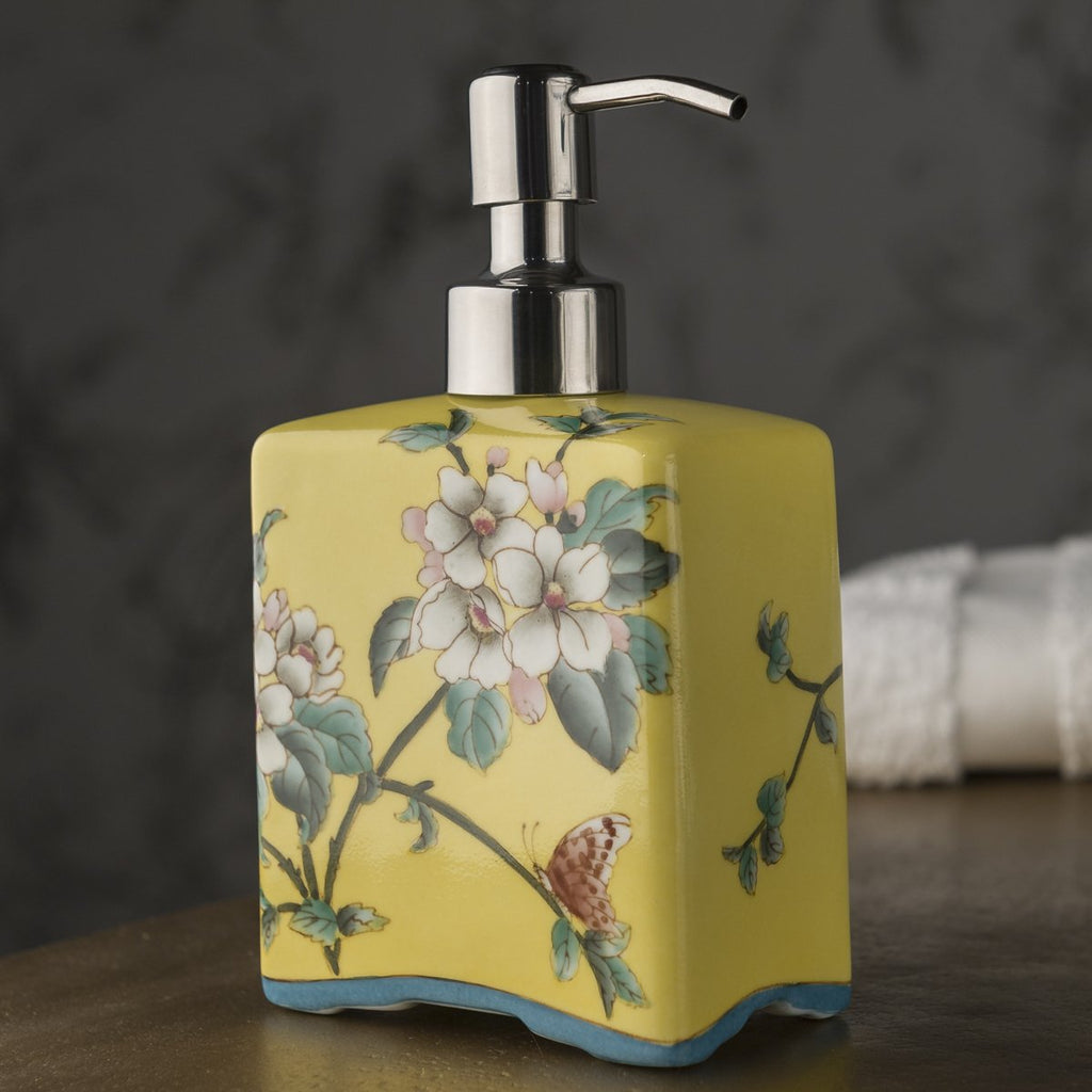 A yellow ceramic soap dispenser hand-painted with colourful blossoms.