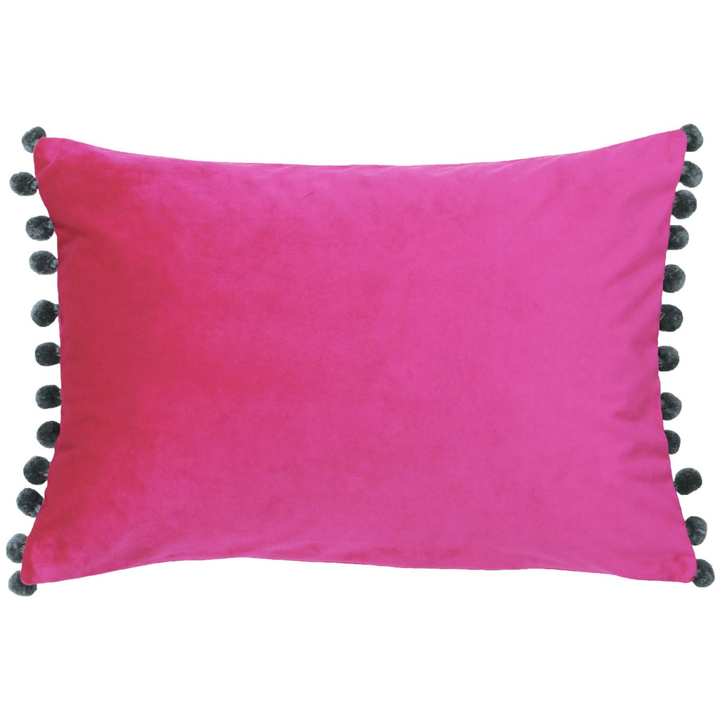 A rectangular cushion with a hot pink velvet cover with grey pom poms. 