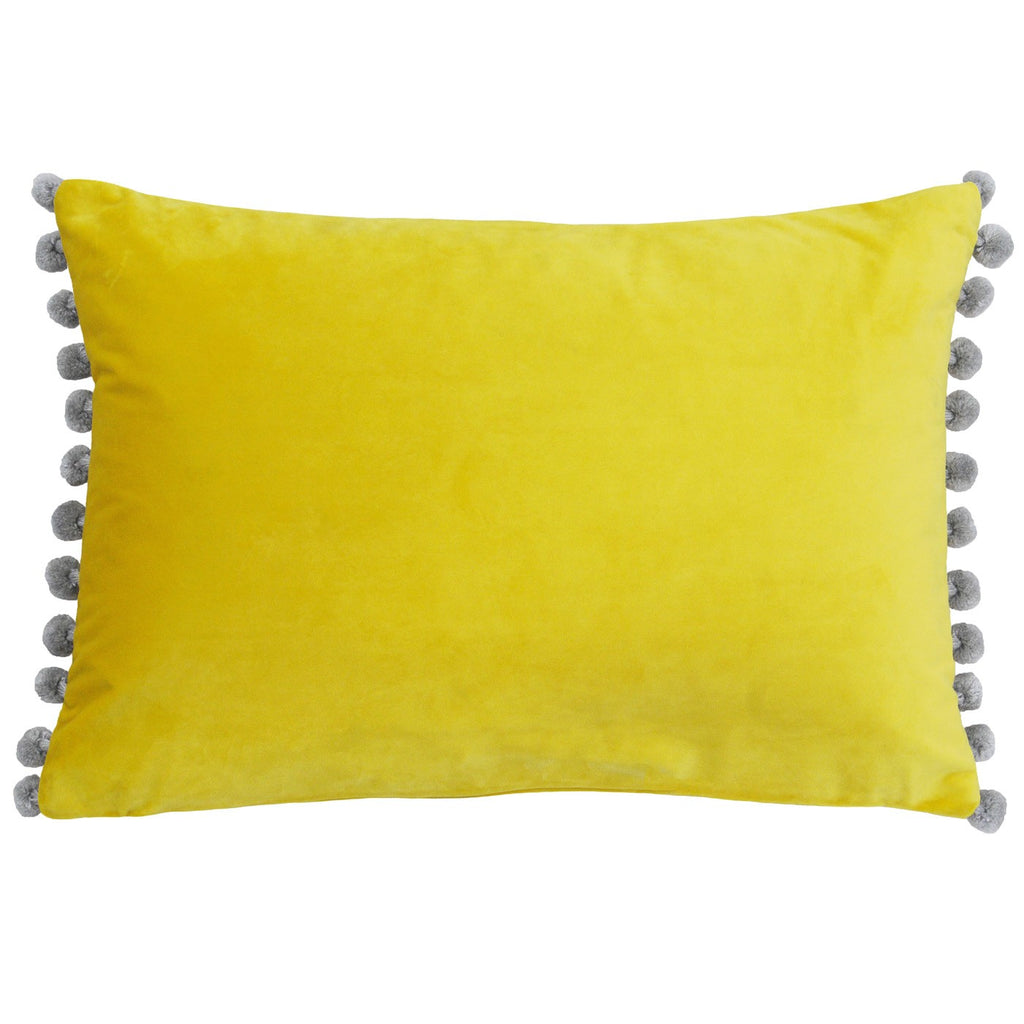 A rectangular cushion with a bright yellow velvet cover, edged on two sides with grey pompoms. 