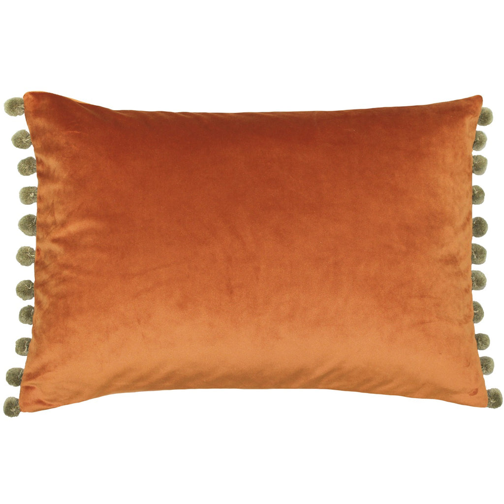 A rectangular cushion with an orange velvet cover edged on two sides with kahki pompoms.