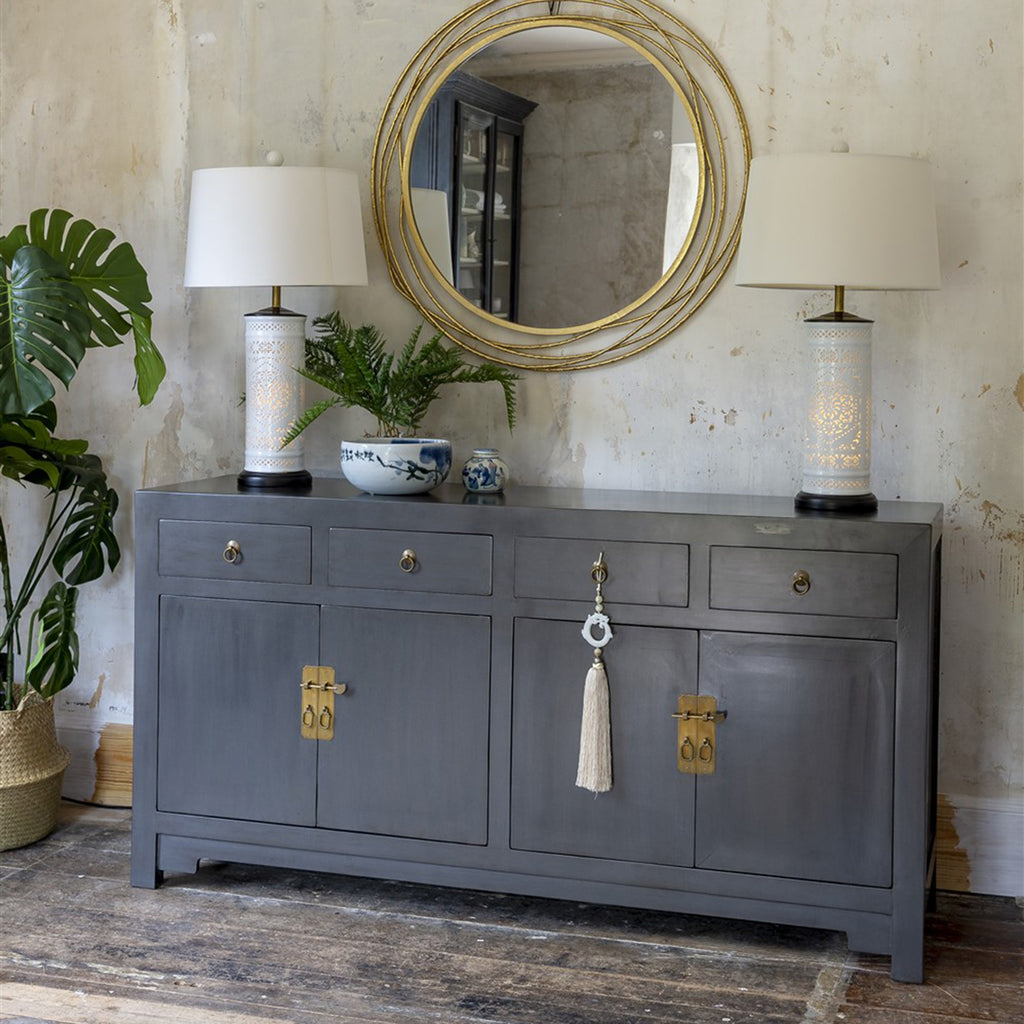 A wooden sideboard with two double door cupboards and four drawers. It features gold brass handles and is finished in a gunmetal grey lacquer. 