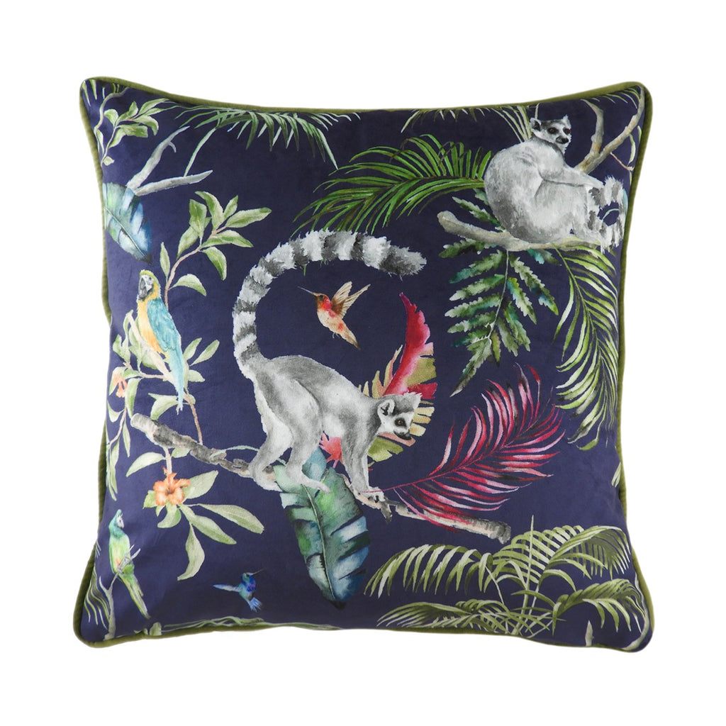 A large square navy cushion covered in velvet and decorated with a green piping and tropical flora and forna, predominantly lemurs. 