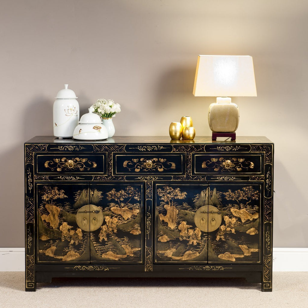 A Chinoiserie sideboard with two double door cupboards and three drawers. The cupboards feature Chinese lock and pins and the black colour base is hand-painted in gold with traditional rural scenes.