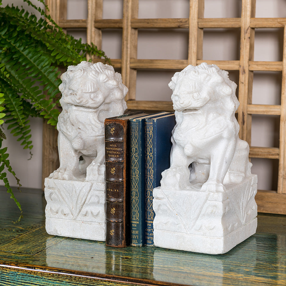 Two white stone Chinese Foo Dogs, hand-carved and being used as bookends. 